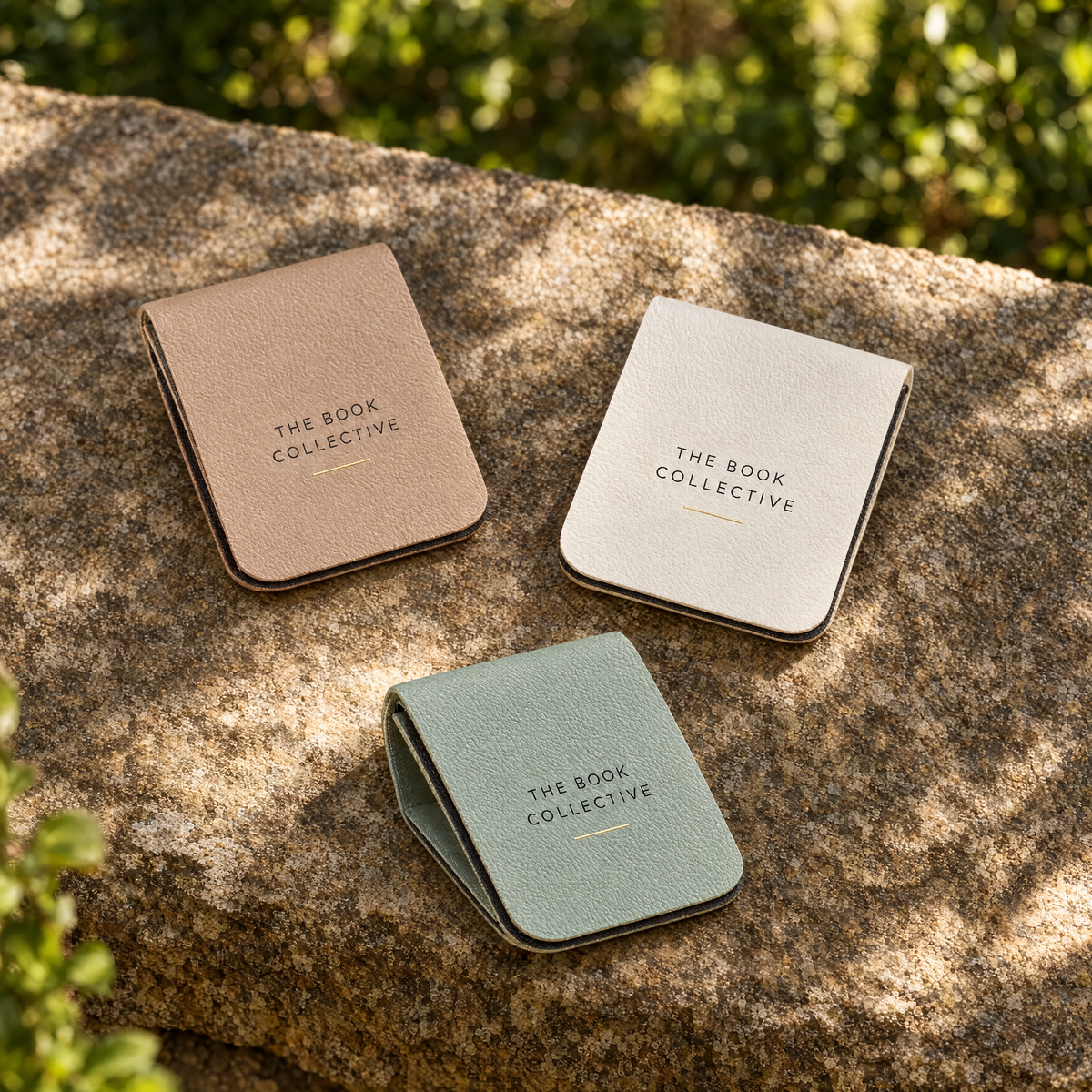 Three branded faux-leather magnetic bookmark clips in beige, ivory and muted green, based on the Alibaba supplier's product form.